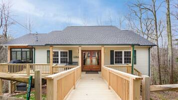 A two-story house with a covered porch, a wooden deck, and a number '1584' on the front door.