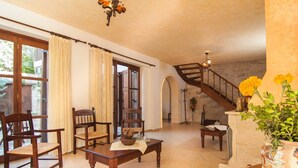 Ein geräumiges Wohnzimmer mit Holzmöbeln, einer Treppe und Blick ins Freie.
