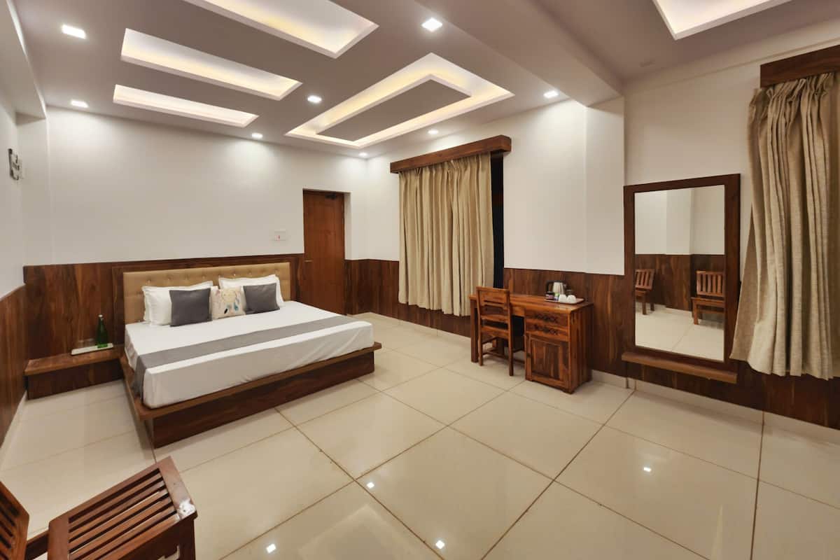 Una habitación de hotel moderna con una cama grande, un escritorio de madera y un espejo.