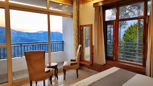 Habitación con amplia ventana que ofrece vistas a la montaña, techo de madera y cama con vista.