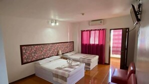 Ein Hotelzimmer mit zwei Betten, einem roten Sofa, einem Holzboden und Blick nach draußen.