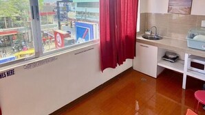 Una habitación con un ventanal grande, un lavabo, un espejo y una silla roja.