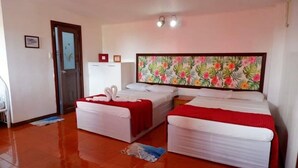 Habitación de hotel con dos camas, un refrigerador, una puerta y una pared con estampado floral.
