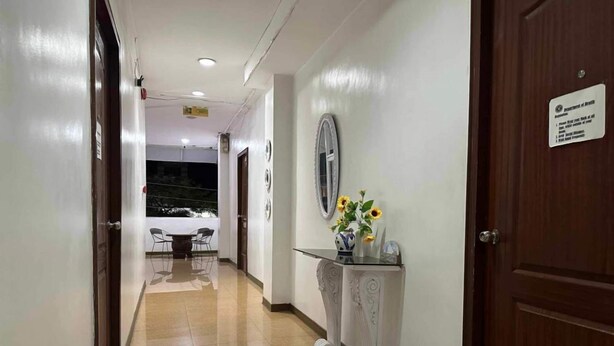 A clean, well-lit hallway with a marble floor, a reception desk with a vase of sunflowers, and a sign indicating a health center.