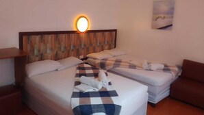Et hotelværelse med to senge, en træsenggavl, en vægmonteret lampe og et maleri.