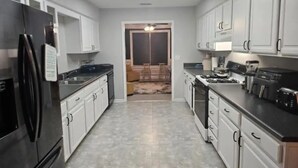 A kitchen with white cabinets, a black refrigerator, and a gas stove.