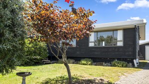 Une maison moderne à l’extérieur sombre, dotée d’une fenêtre bien visible et d’une pelouse bien entretenue.