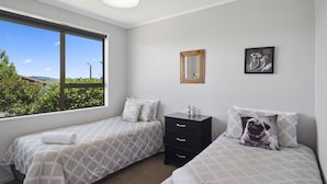 Une chambre avec deux lits, une commode, un miroir et un tableau encadré au mur.