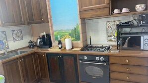 Una cocina con armarios de madera, estufa a gas, microondas y cafetera.