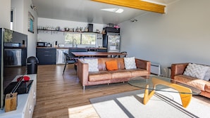 Une cuisine moderne dotée d’un îlot central, un coin repas avec des canapés en cuir et un salon avec une table basse en verre.