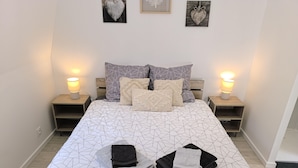 A neatly made bed with geometric patterned bedding, two bedside tables with lamps, and a wall with framed artwork. - « Modern Cosy » Hyper Centre Bernay (Bernay)