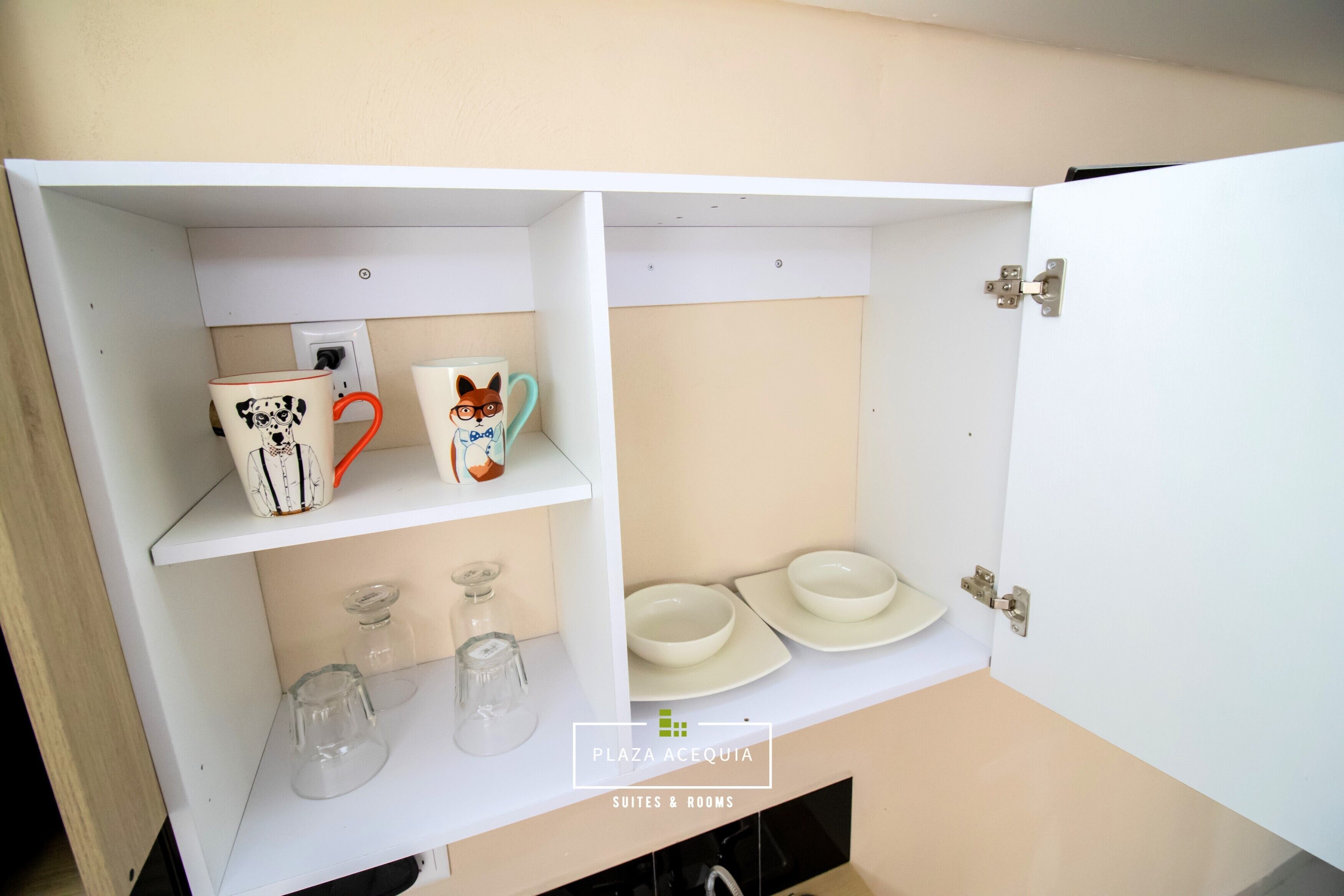 Un gabinete blanco con estantes que contienen tazas, cuencos y vasos.