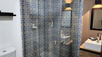 A bathroom with a glass-enclosed shower, a toilet, a sink, and a mirror.