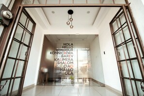 Welcome to Plaza Ace, where guests are greeted with a modern entrance featuring a large glass door and pendant lights.