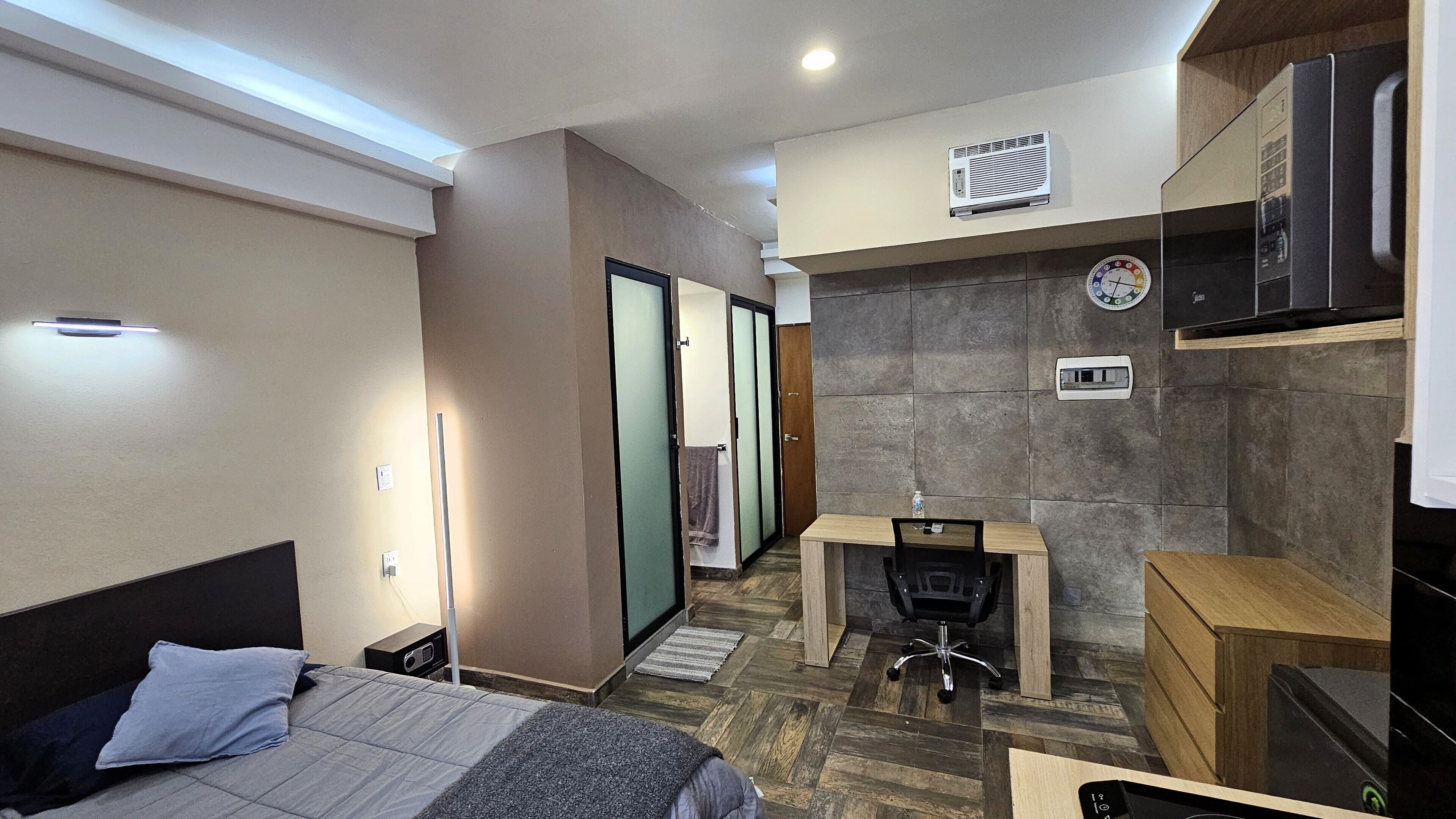 A modern hotel room with a bed, desk, chair, and a TV.