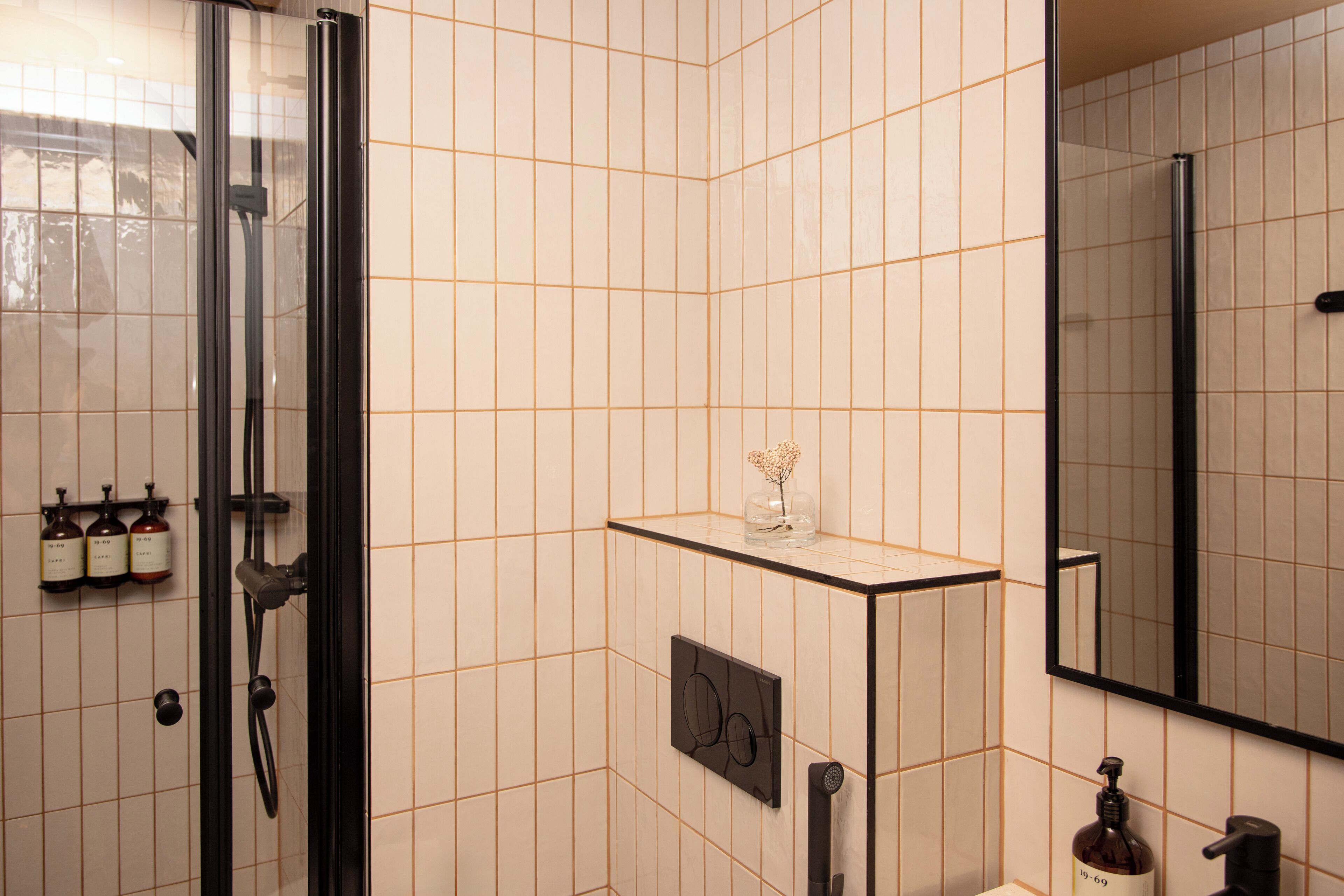 Un bagno moderno con cabina doccia in vetro, un lavabo con specchio e articoli da toilette a parete.