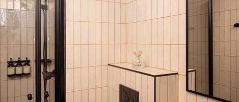 Un baño moderno con cabina de ducha de vidrio, un lavabo con espejo y artículos de aseo en la pared.