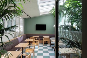 Un restaurante con piso a cuadros, paredes verdes y un televisor de pantalla plana montado en la pared.
