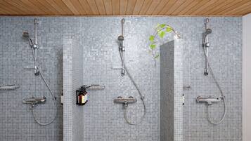 Un bagno con tre soffioni doccia e una parete rivestita in piastrelle.