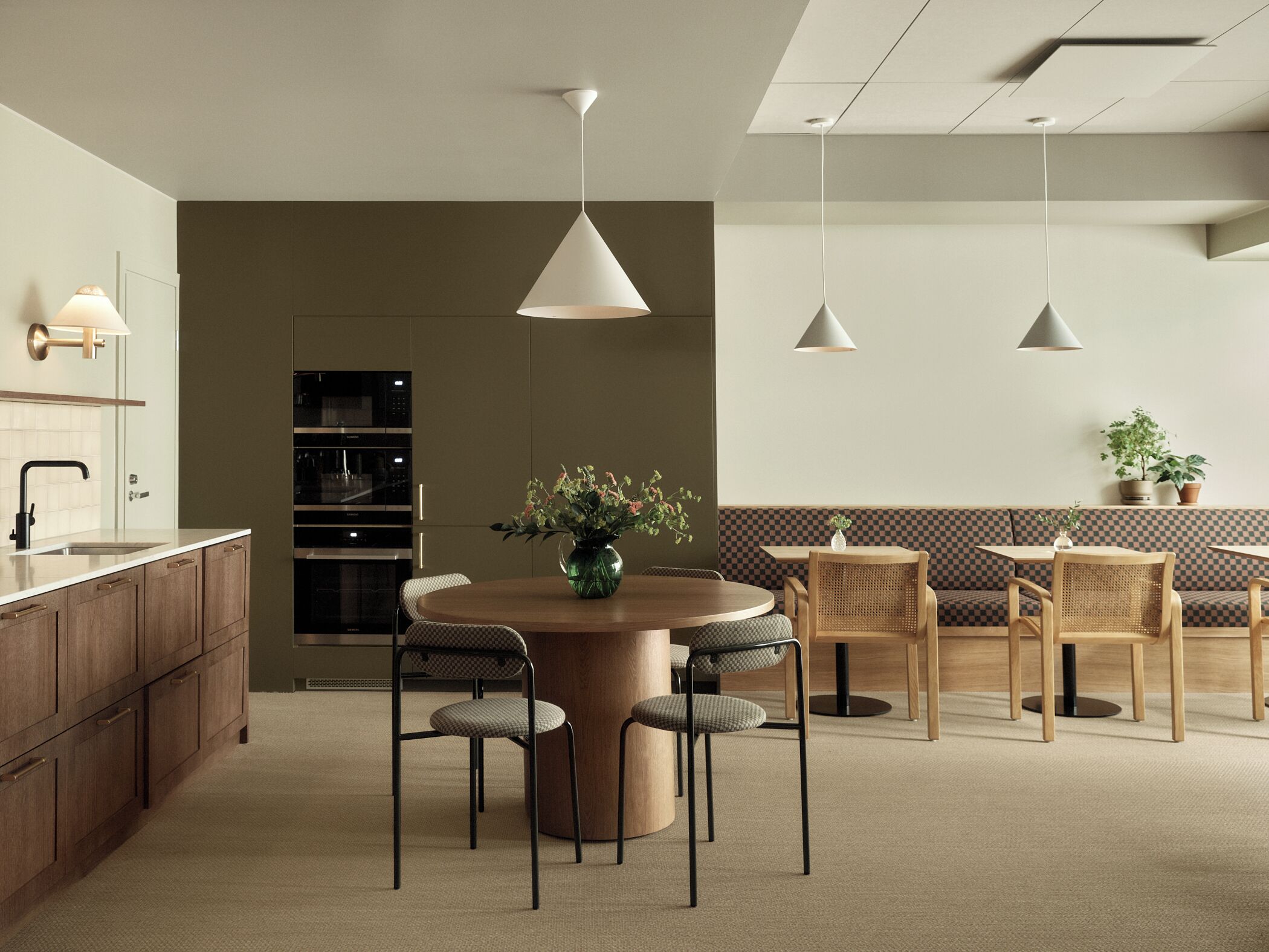 A modern kitchen with a central island, built-in oven, and a dining area with a round table and chairs.