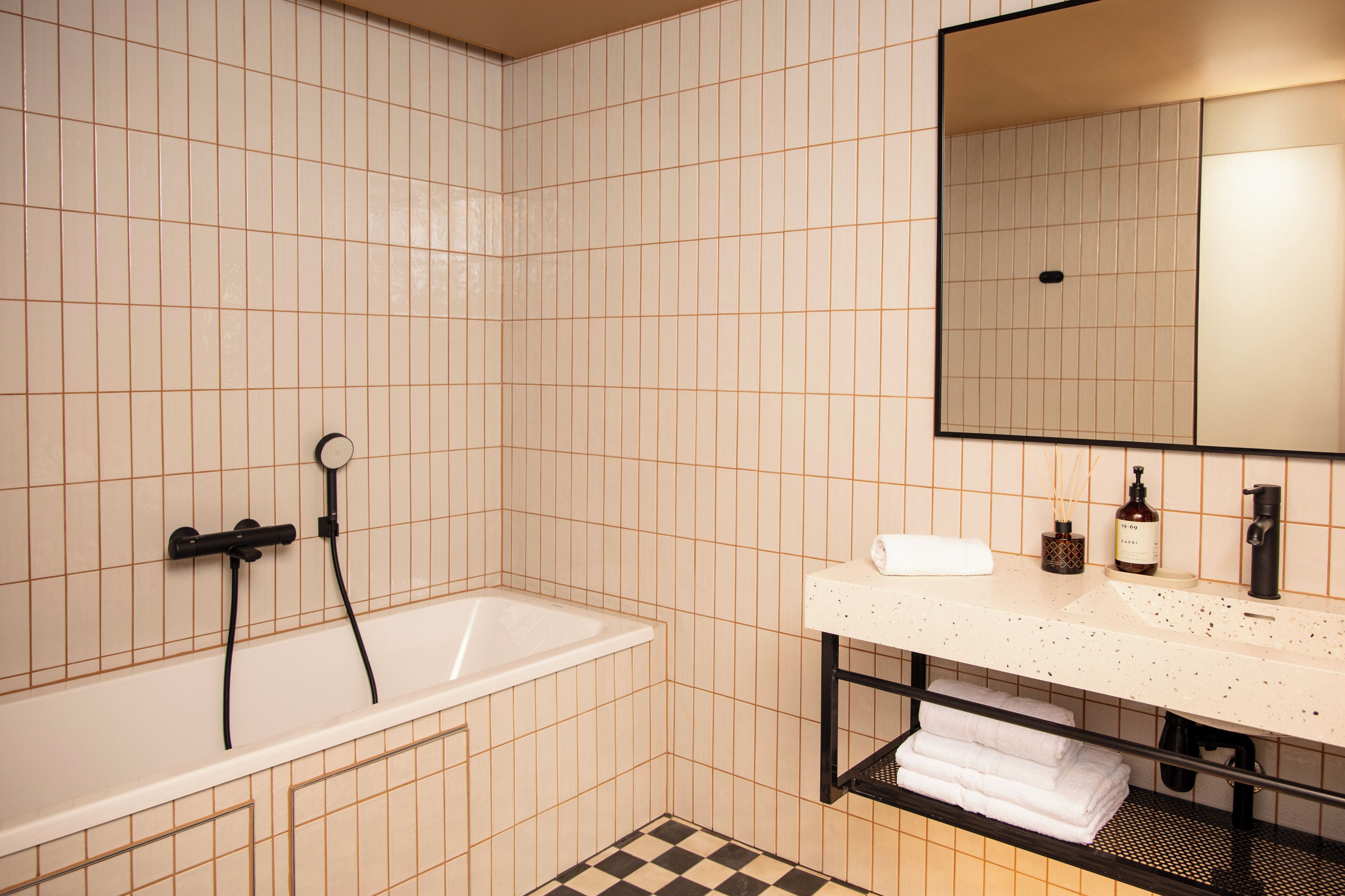 A bathroom with a bathtub, a sink, a mirror, and a shelf with towels.