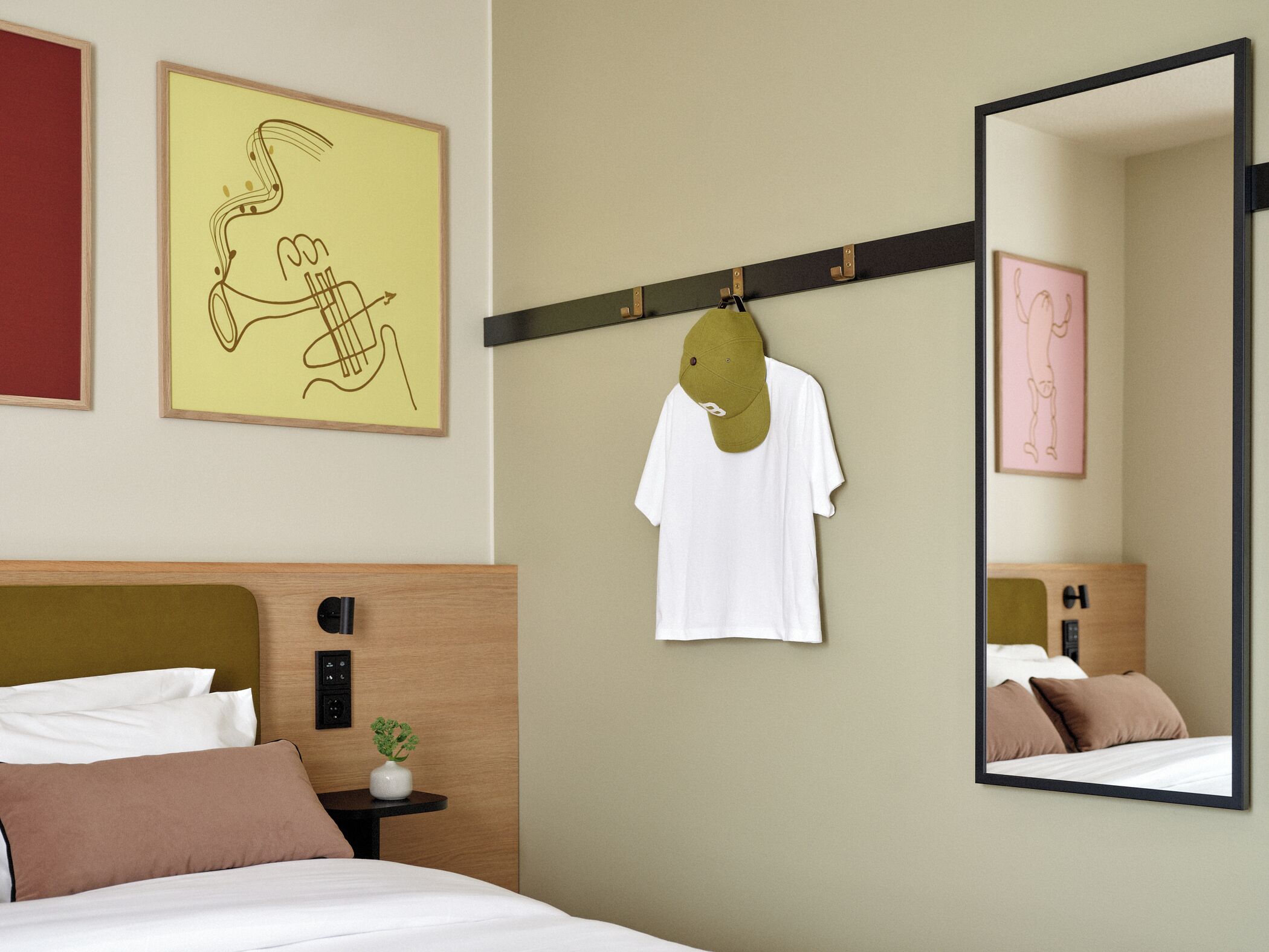 A hotel room with a bed, a nightstand, a mirror, and artwork on the walls.