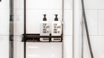 A bathroom with two bottles of 'Stop the Water While Using Me!' shampoo on a shelf.
