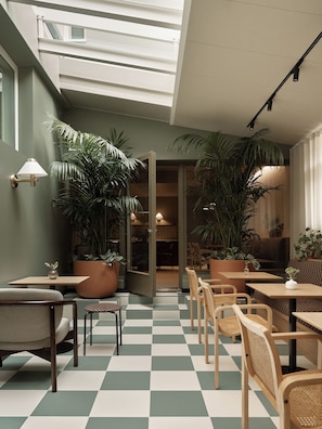 A cafe with checkered flooring, wooden furniture, and large potted plants. - Bob W Helsinki Kaarti (Helsinki)