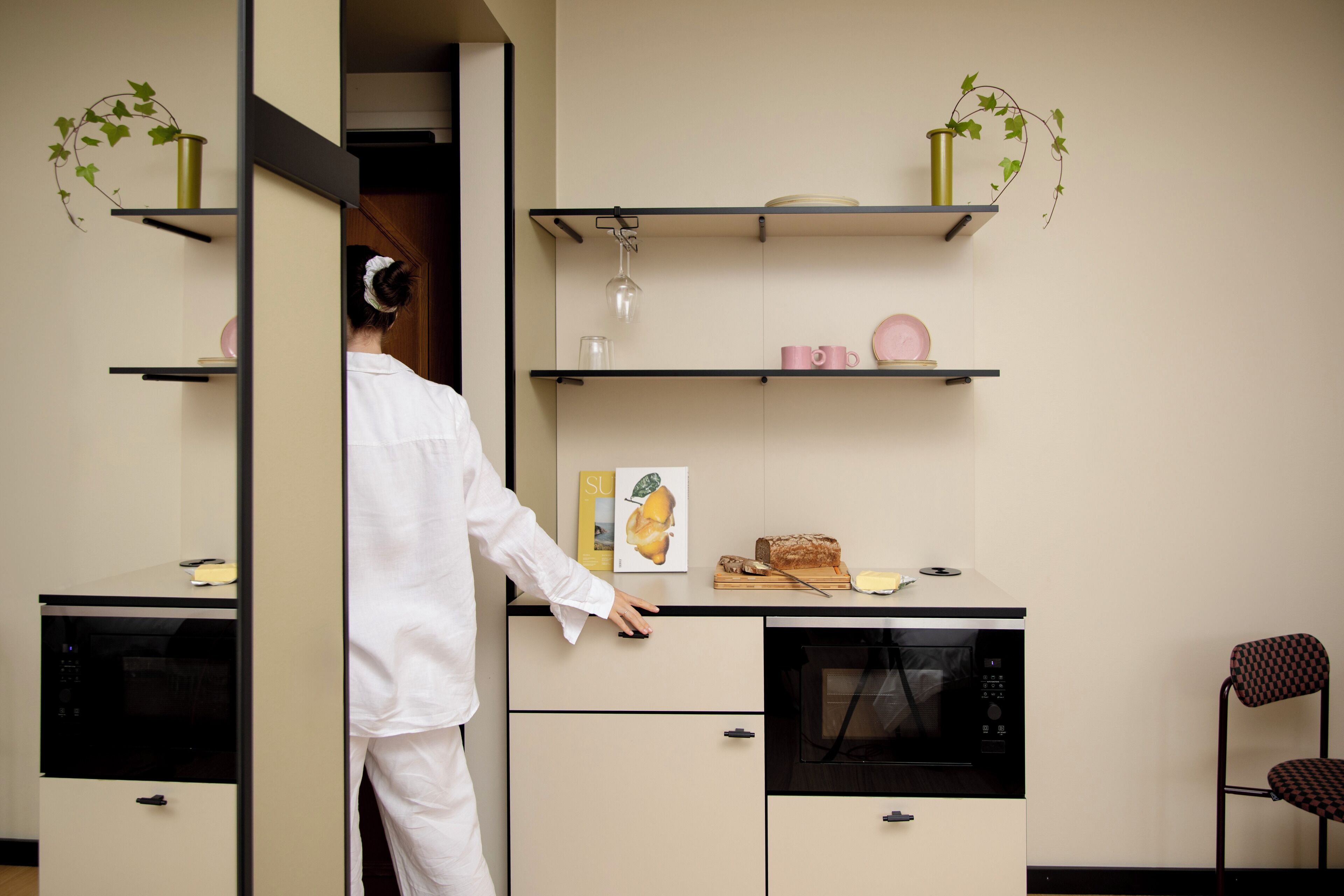 A compact kitchen with built-in appliances, a microwave, and a small dining area with a chair.