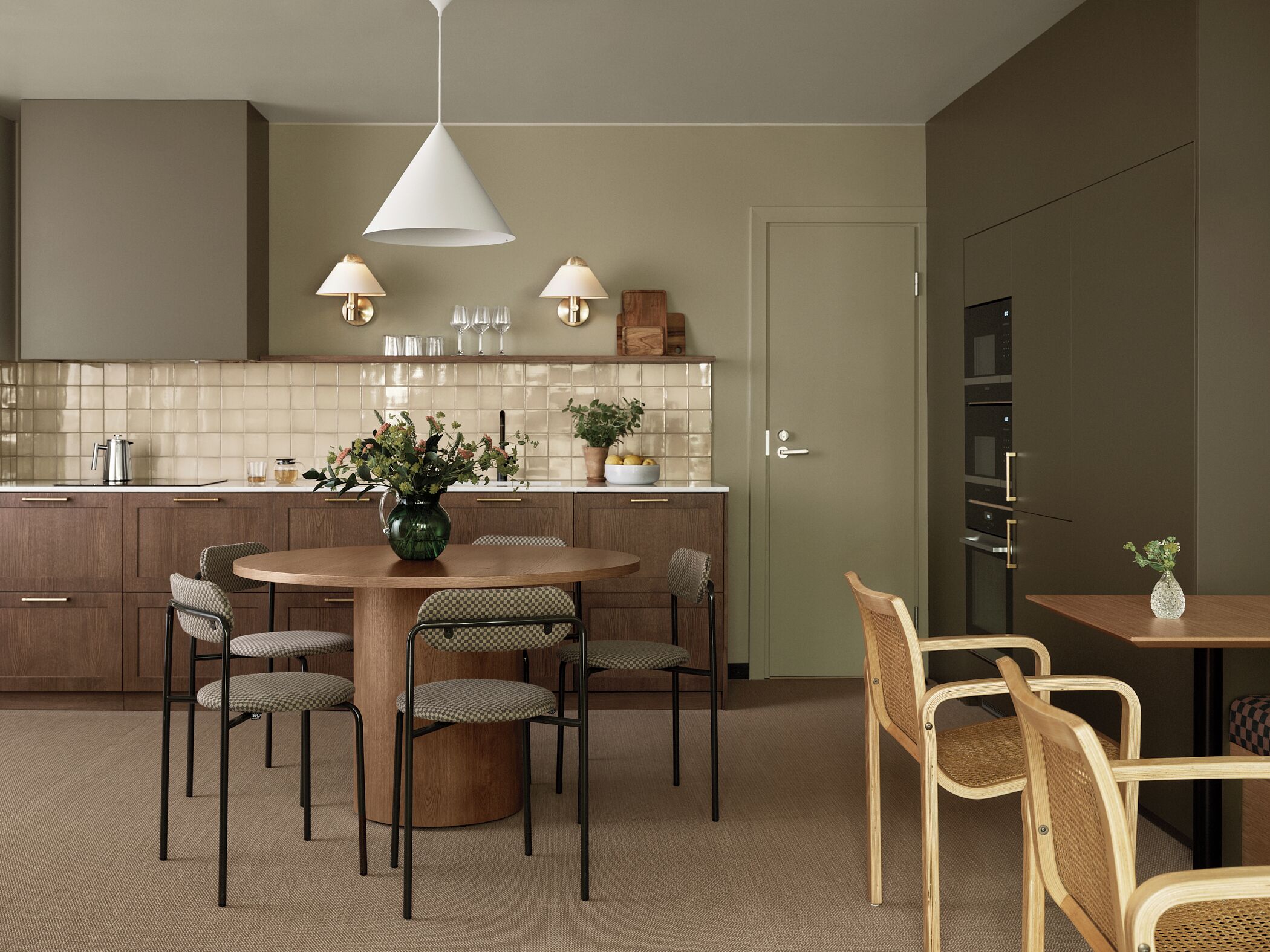 A modern kitchen with a round dining table, four chairs, and a hanging light fixture.