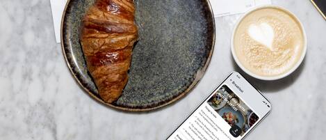 Un croissant sur une assiette, une tasse de café et un menu sur la table.