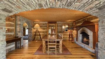Un intérieur rustique avec un mur en pierre, un plancher en bois, une cheminée et un coin repas.