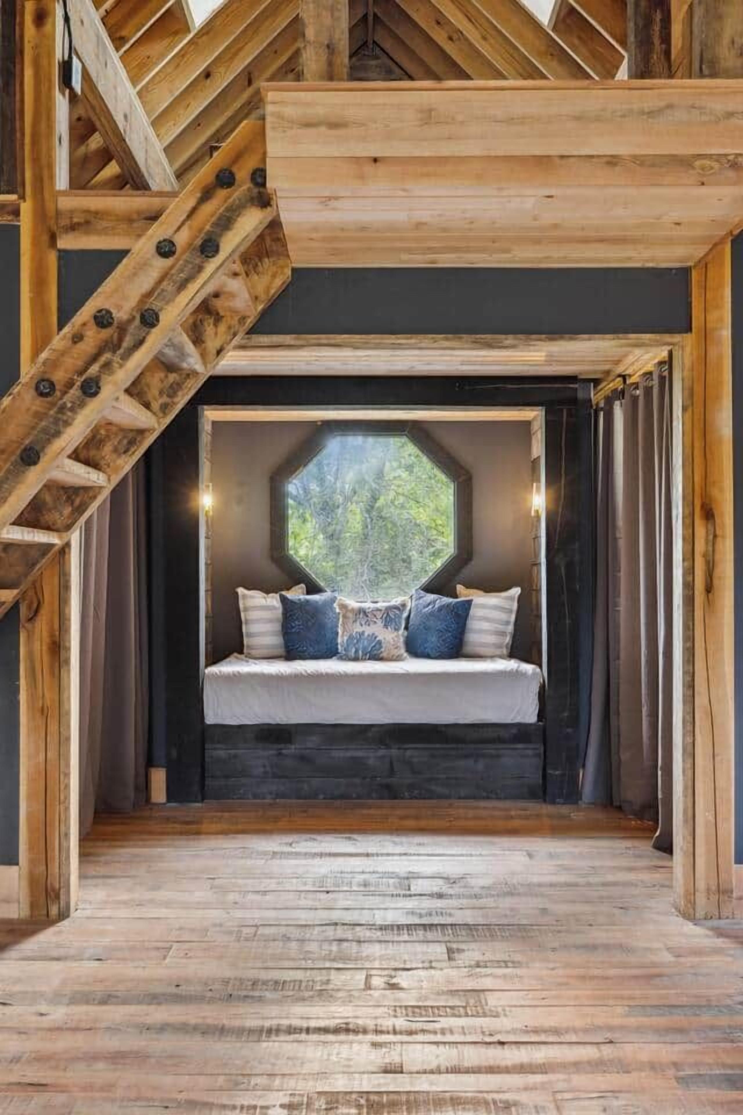 Una habitación con techo inclinado, una escalera de madera y una cama con almohadas.