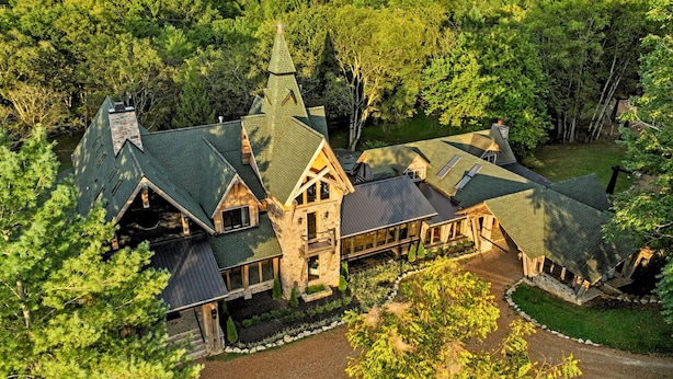 A large, multi-story lodge with a prominent tower and steeply pitched roofs, surrounded by dense forest. - Extraordinary Manor at Dark Horse Retreat (Franklin)