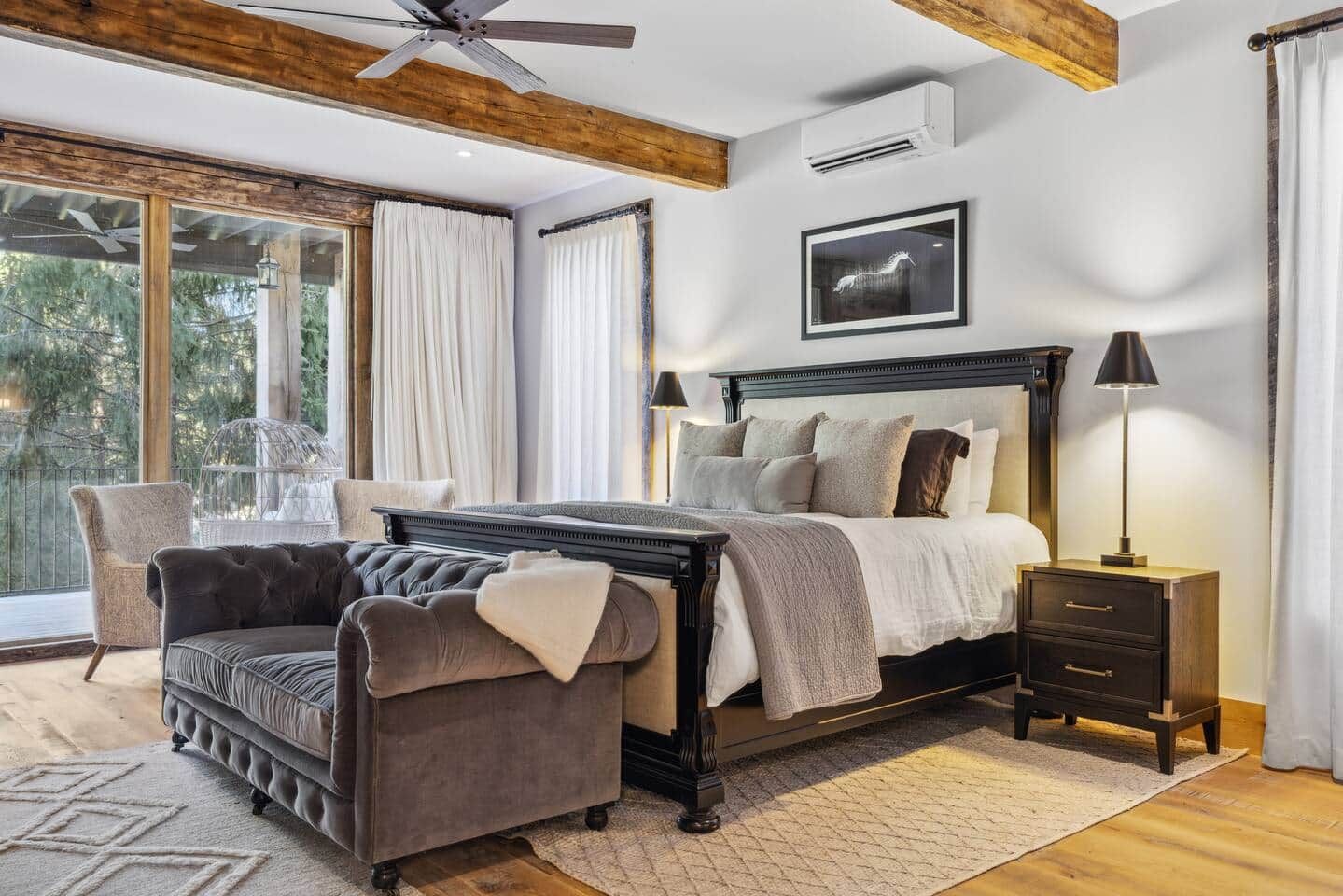 A bedroom with a bed, bedside tables, a chair, and a large window.