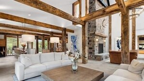 A spacious living room with a white sectional sofa, a wooden coffee table, and a stone fireplace. - Extraordinary Manor at Dark Horse Retreat (Franklin)