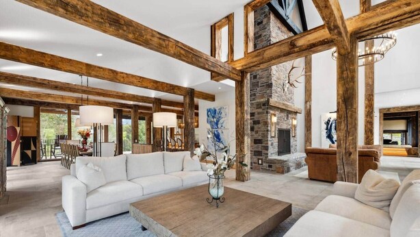 A spacious living room with a white sofa, a wooden coffee table, and a stone fireplace.