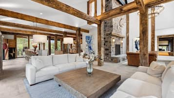 A spacious living room with a white sofa, a wooden coffee table, and a stone fireplace.
