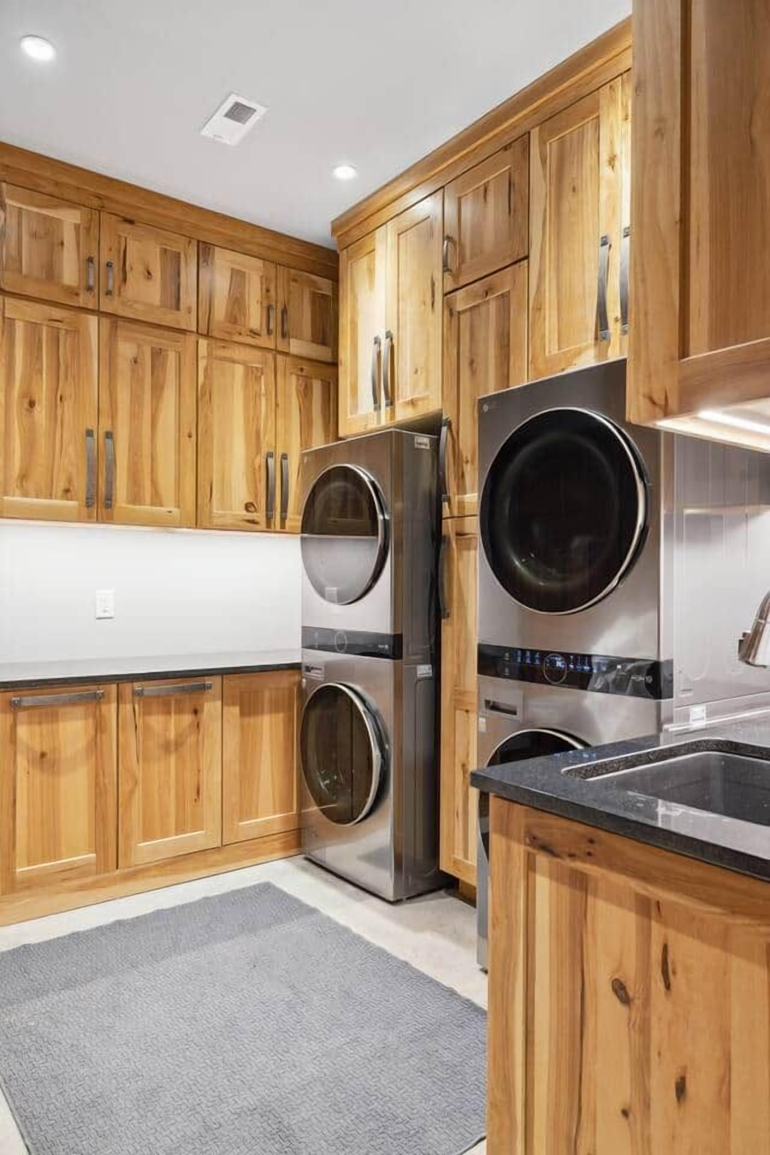 A kitchen with wooden cabinets, stainless steel appliances, and a grey rug.