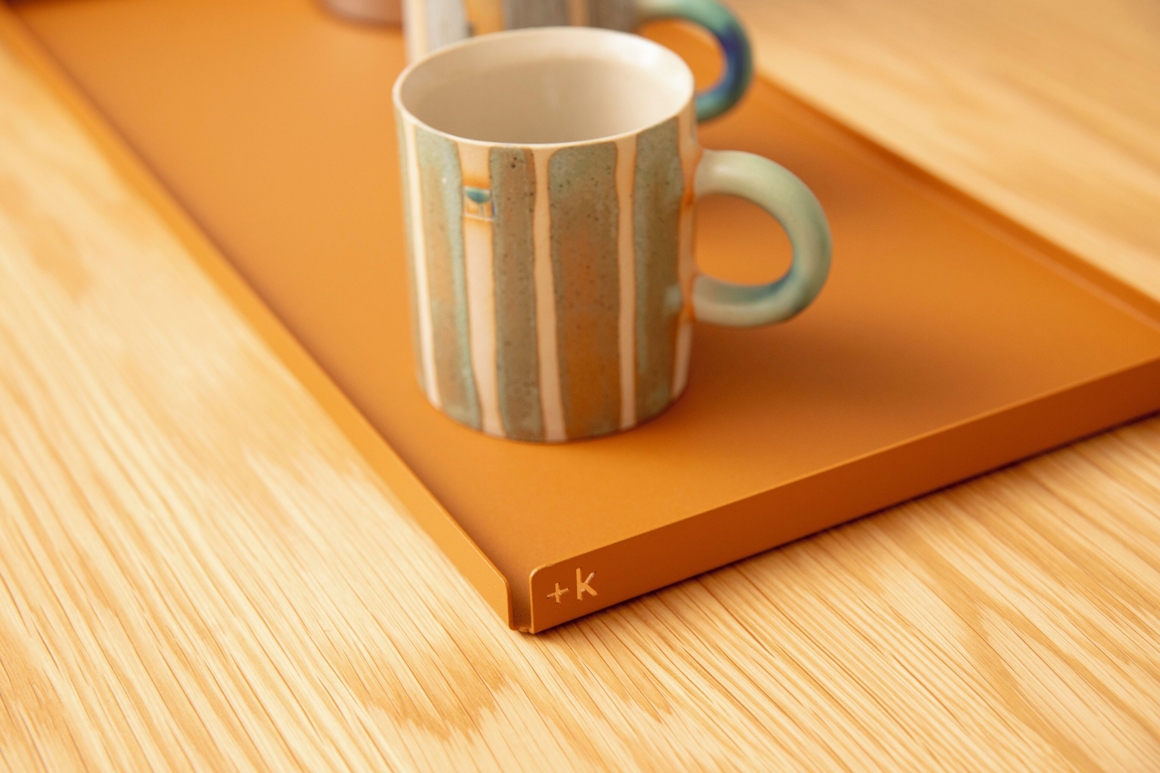A mug with a striped pattern on a wooden tray.