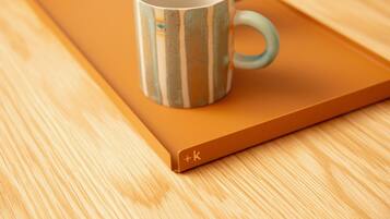 A mug with a striped pattern on a wooden tray.