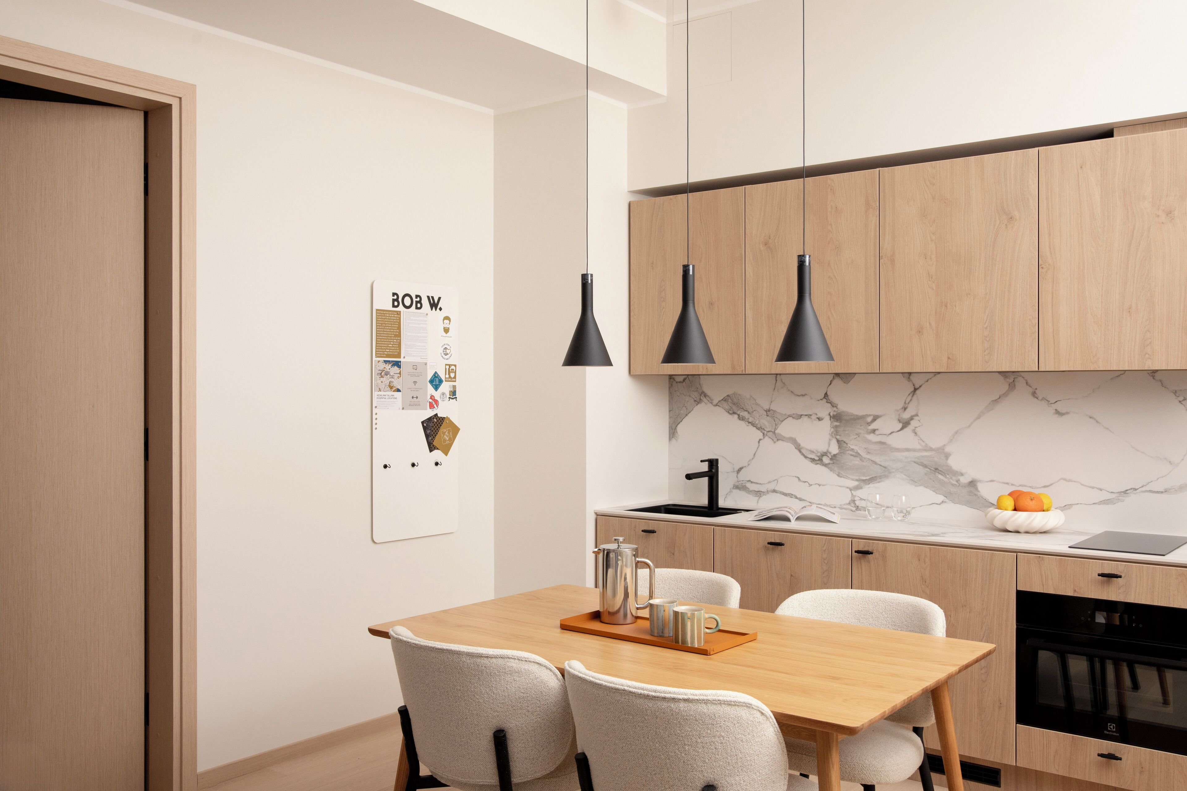 Eine moderne Küche mit Holzausstattung, Marmorfliesenspiegel und Pendelleuchten.