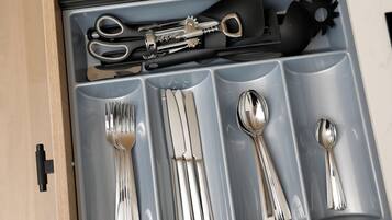 A drawer with compartments containing various utensils including forks, knives, and spoons.
