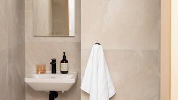 A bathroom with a white sink, a mirror, a towel hanging on a rack, and a door with a handle.