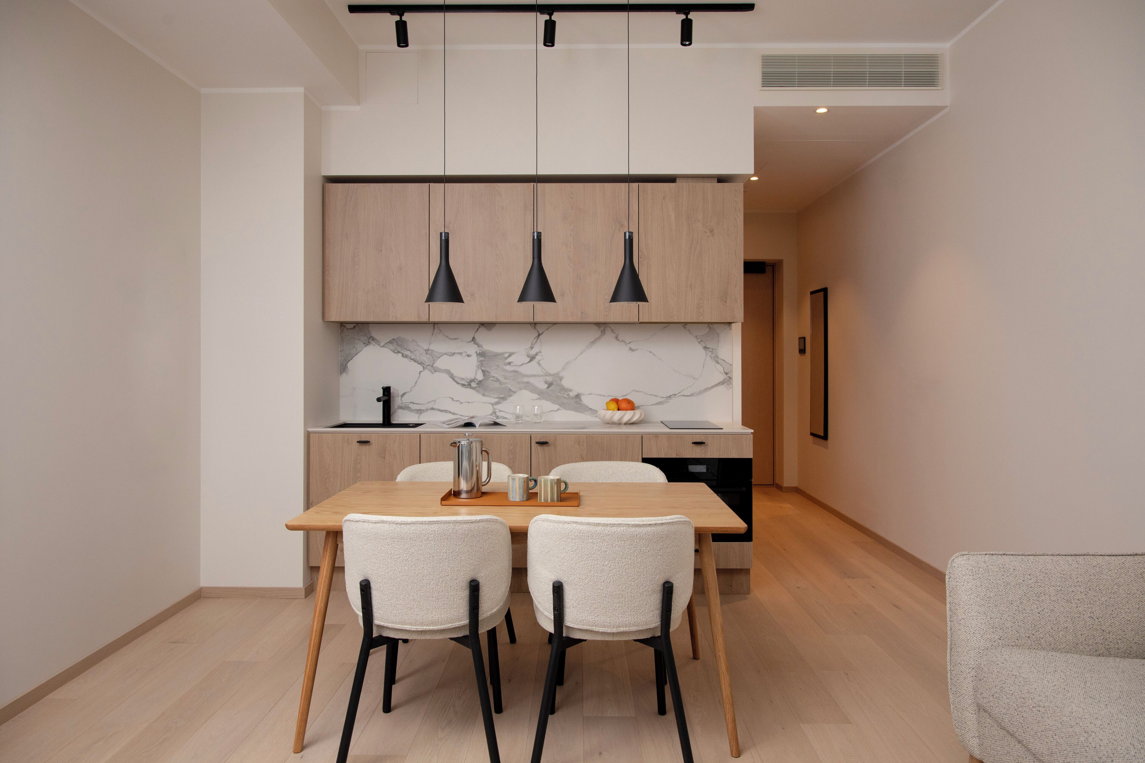 Uma cozinha moderna com armários de madeira, painel de backsplash de mármore e iluminação pendente.