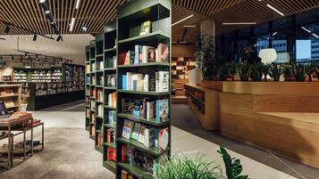 L’intérieur moderne d’une bibliothèque, avec des étagères vertes, un comptoir d’accueil en bois et des plantes d’intérieur.