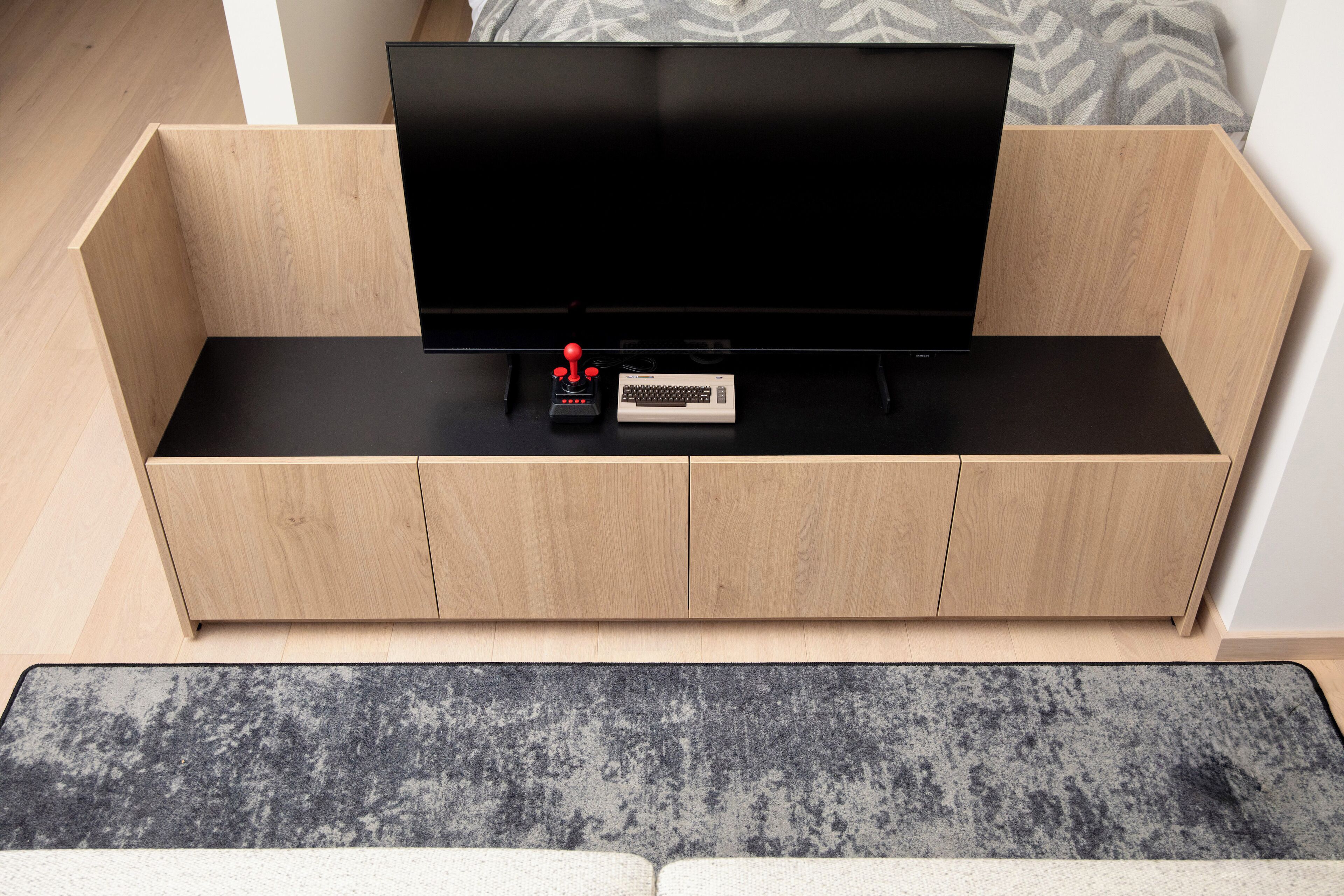 A modern living room with a flat-screen TV on a wooden console, a remote control, and a small console table.