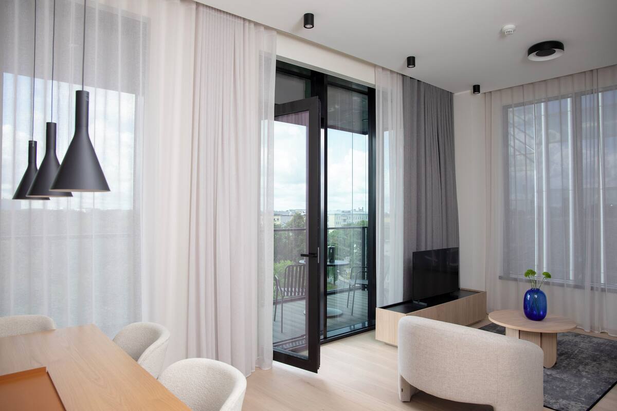 Una sala de estar moderna con un televisor grande, un sofá, una mesa de centro y un balcón con vistas.
