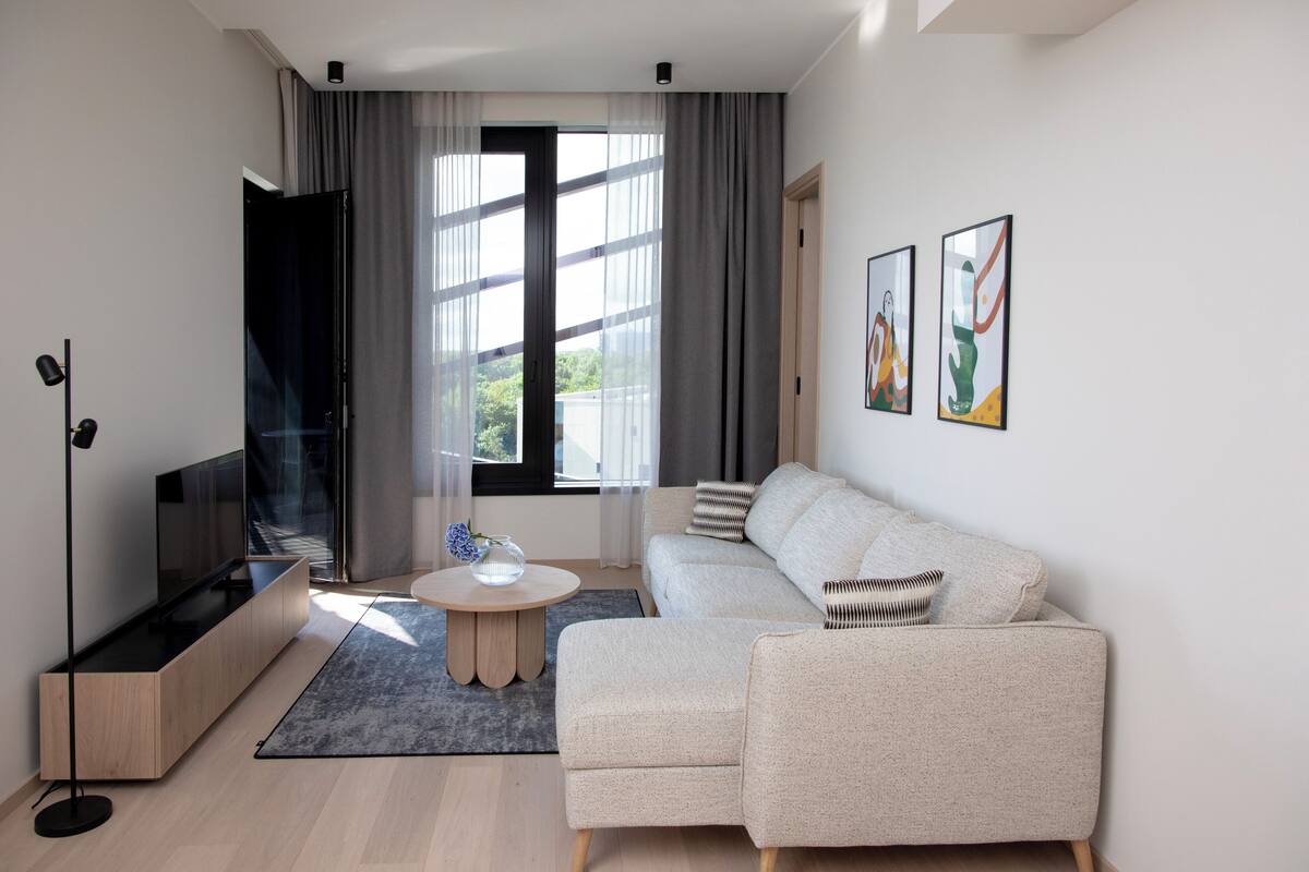 Una sala de estar moderna con un sofá, un televisor, una mesa de centro y obras de arte en la pared.