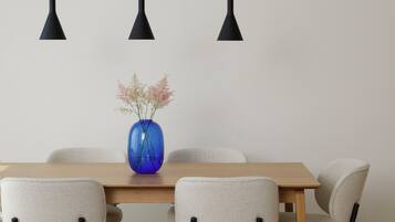 A dining area with a wooden table, six chairs, and three pendant lights.